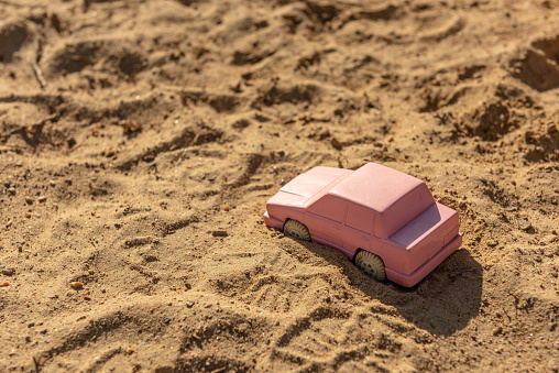 Pink toy car in the sand at a playground