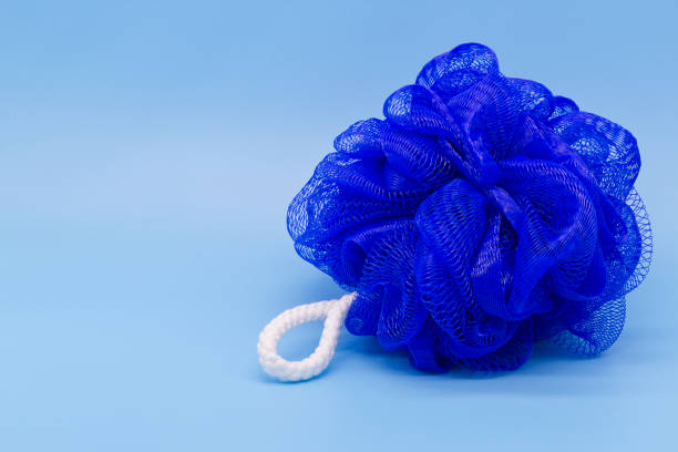istock Blue mesh pouf bath sponge washcloth single object on blue background closeup photo with copy space. Soft synthetic shower wash cloth. Washing hygiene design element. Spa body care accessory product 1402727439