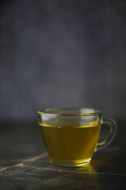 istock Illuminated brewed herbal green tea in a transparent cup on a dark background. Vertical style 1402727498