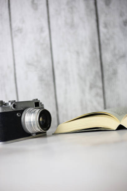 istock Vintage camera next to an open book on a light background 1402728318