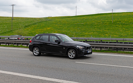 Kempten, Allgäu, Schwaben, Bavaria, Germany, may 1st 2022, a black German BMW X1 from the Ilm-Kreis district approaching on the German A7 Autobahn at Kempten - with a length of 963 km between the borders of Denmark in the north and Austria in the south, the Autobahn 7 is the longest Autobahn in Germany - the majority of the German Autobahn does not have a mandatory but only an advisory speed limit
