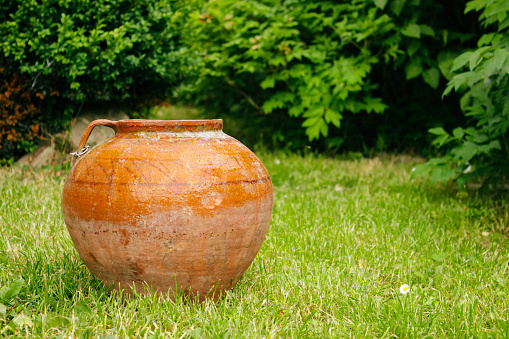 Vintage Old traditional clay pot of orange color on grass outdoor
