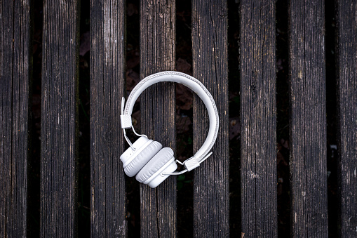 White headphones on a wooden background, flat lay, copy space.