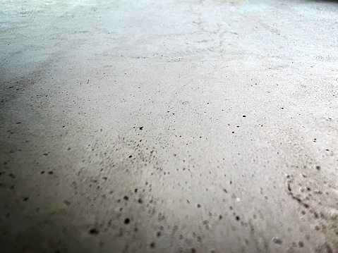Macro image of a very fine concrete with small holes and traces of use.