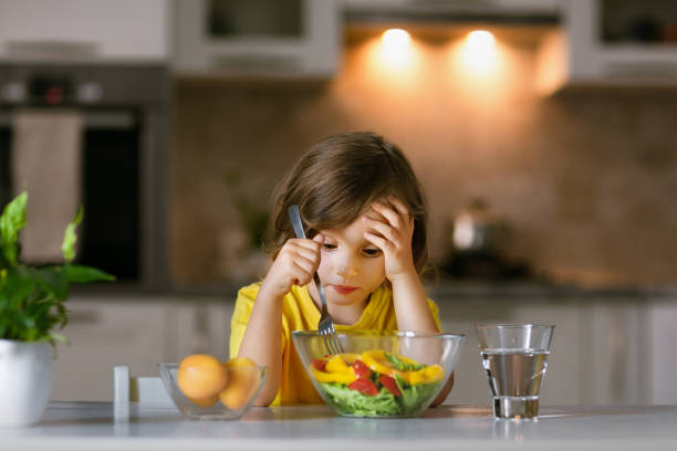istock Problems with teaching a child to eat a healthy salad from fresh ingredients and to proper nutrition 1402736954