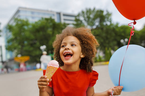 istock a black laughing child with ice cream in a waffle cone at summer day 1402737039