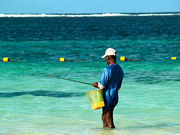 Preteen African-american boy on his first sea fishing trip on a boat. He is firmly holding his fishing rod against the wind trying to bring back his catch. Horizontal waist up shot outdoors with copy space. This was taken in Florida, USA.