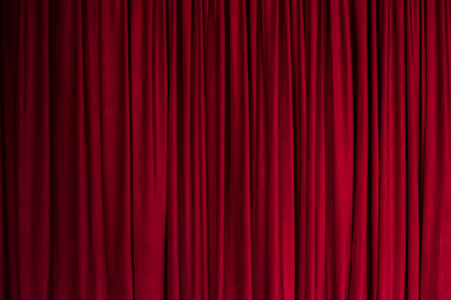 Red background, texture of a red curtain with pleats, theater curtain.