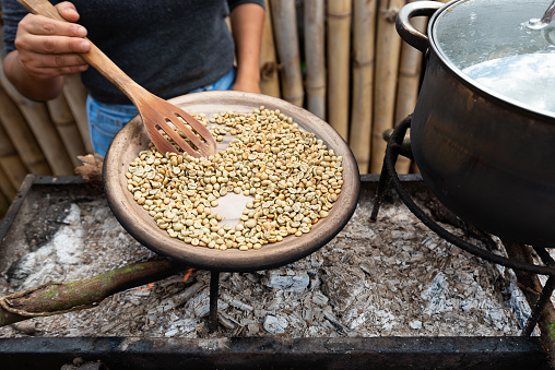 Entire process of traditional coffee roasting over fire on a clay tray outdoor