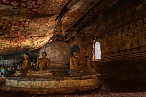 Buddha statue inside Dambulla cave temple, Sri Lanka. Dambulla cave temple also known as the Golden Temple of Dambulla is a World  Heritage Site in Sri Lanka, situated in the central part of the country. This site is situated 148 km east of Colombo and 72 km  north of Kandy. It is the largest and best-preserved cave temple complex in Sri Lanka. This temple complex dates back to the first century BCE. There are more than 80 documented caves in  the surrounding area. Major attractions are spread over 5 caves, which contain statues and paintings. These paintings and statues  are related to Lord Buddha and his life. There are total of 153 Buddha statues, 3 statues of Sri Lankan kings and 4 statues of  gods and goddesses.
The caves built during the Anuradhapura (1st century BC to 993 AD) and Polonnaruwa times (1073 to 1250), are the most impressive of Sri Lanka's caves.