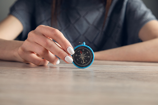 A women holds a compass in hand on wooden background