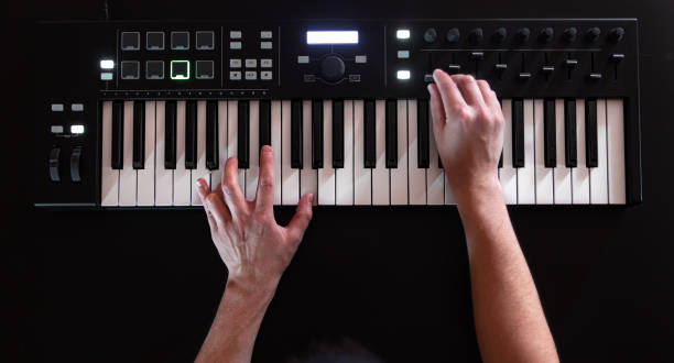 le mani maschili giocano su tasti musicali bianchi su uno sfondo nero. - piano piano key orchestra close up foto e immagini stock