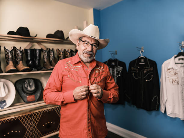 hombre latino maduro que se viste como vaquero mexicano - abrochar su camisa fotografías e imágenes de stock