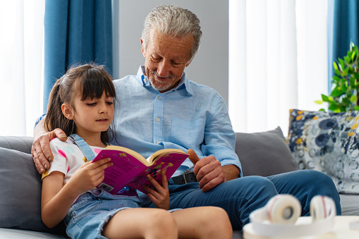 grandfather and granddaughter reading book together