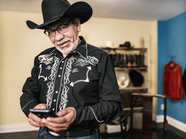 istock Mature Latin man dressed as Mexican Cowboy using mobile phone 1402745094