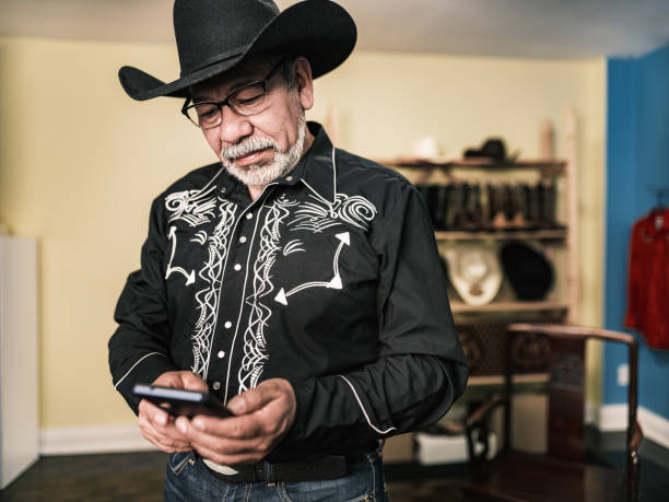 istock Mature Latin man dressed as Mexican Cowboy using mobile phone 1402745116