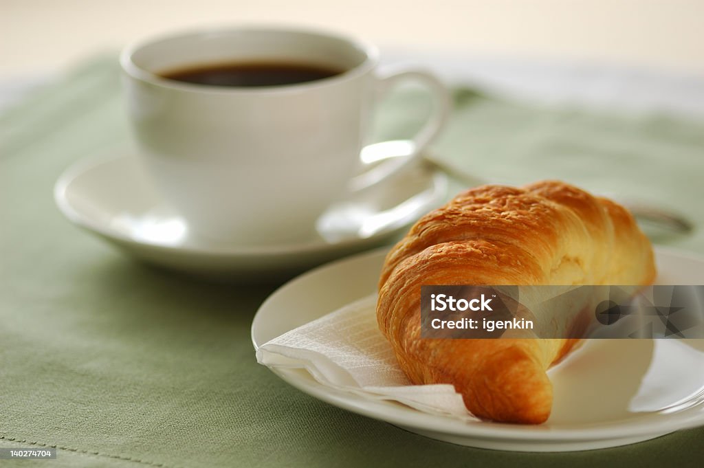 Croissant and coffee 01 Fresh-baked croissant and cup of coffee. Shallow DOF. Focus on croissant. Baked Pastry Item Stock Photo