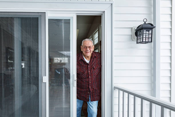 uomo anziano che guarda fuori dalla porta d'ingresso della sua casa - screen door door porch house foto e immagini stock