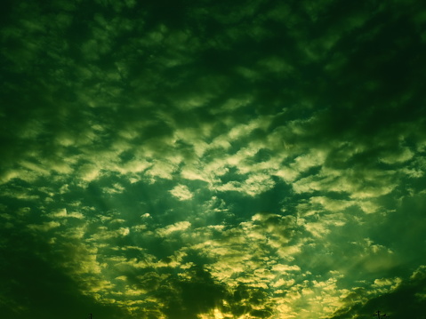 Wonderful sunset. Clouds in the evening sky. The sun's rays pierce the clouds. Green - yellow colors of the sky and clouds. Beautiful landscape. The sun goes down.