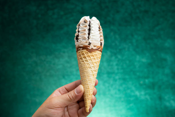 istock hand holding a vanilla and chocolate flavor ice cream cone on a gradient green background 1402761076