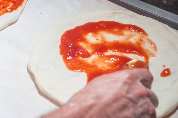 istock Pizza dough with tomato sauce being placed, and mozzarella cheese, pizza concept 1402764456