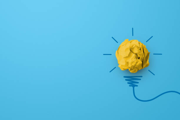 istock Creative thinking ideas and innovation concept. Paper scrap ball yellow colour with light bulb symbol on blue background 1402766157