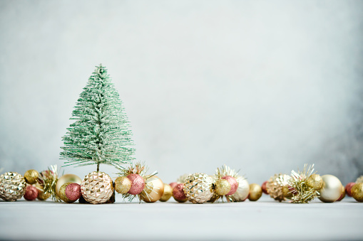 Christmas background with green tinsel tree and glittery gold Christmas decorations. Space for copy
