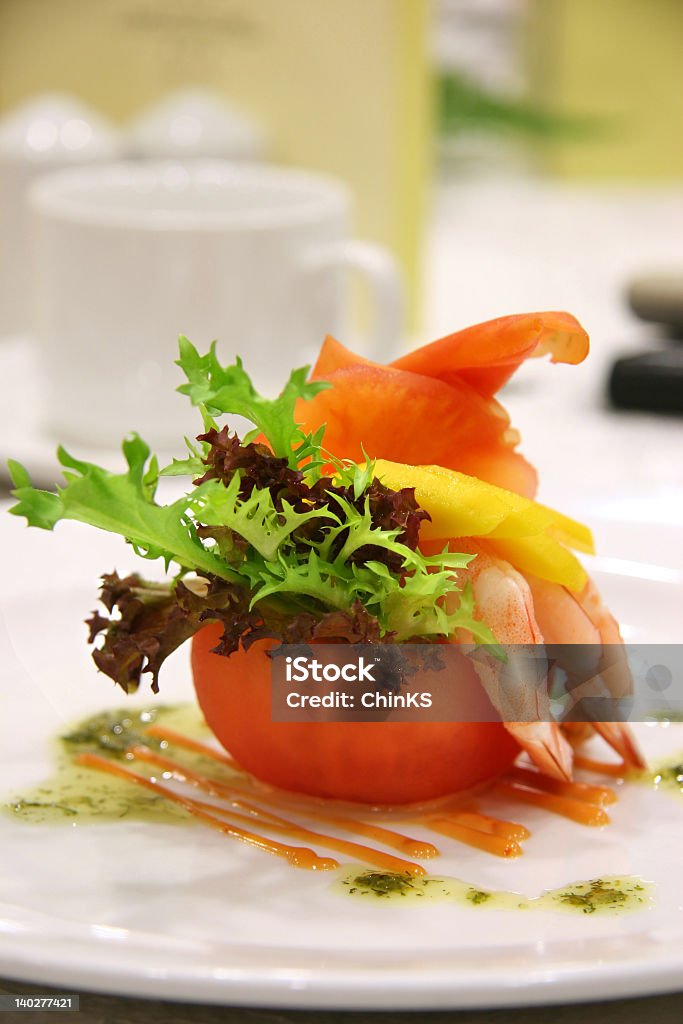 Small orange appetizer with garnish Appetizer of shrimp and mango in a carved out tomato and a dash of different lettuce leaves Animal Shell Stock Photo