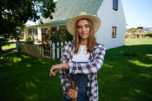Caucasian female farmer smiling standing outdoors leaning on pitch fork. High quality photo