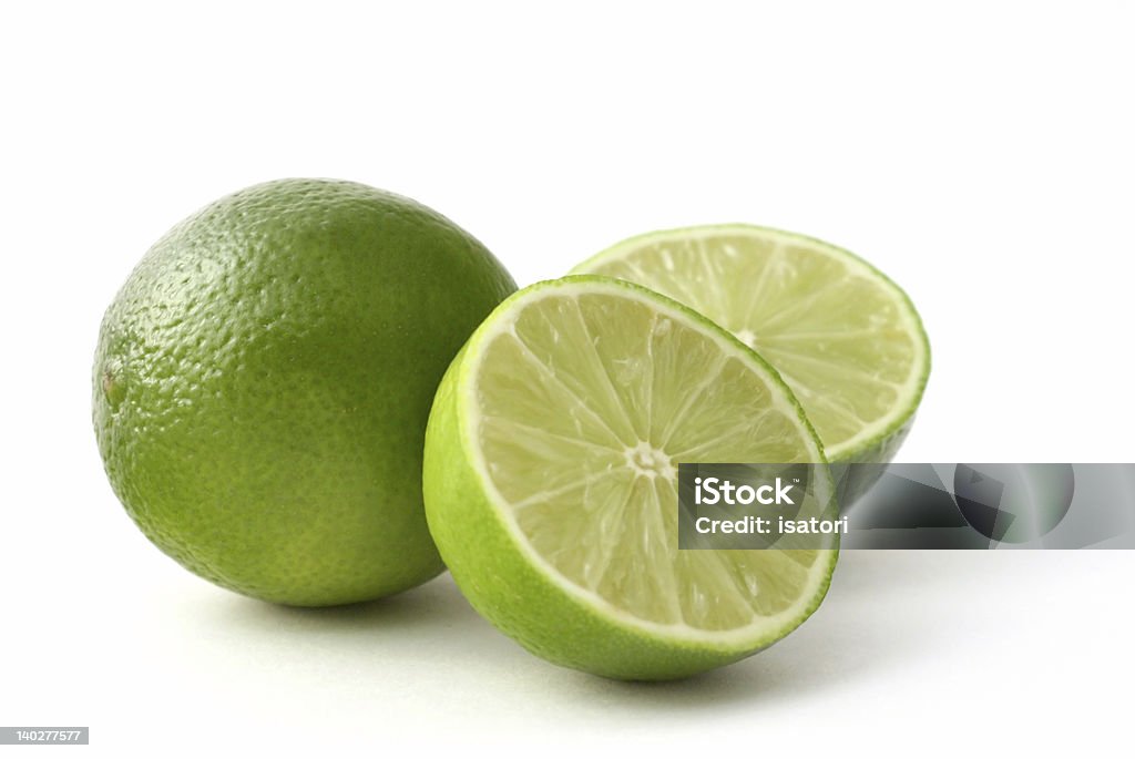 One whole and two half fresh green limes on white background freshly cut limes on a white back ground Acid Stock Photo