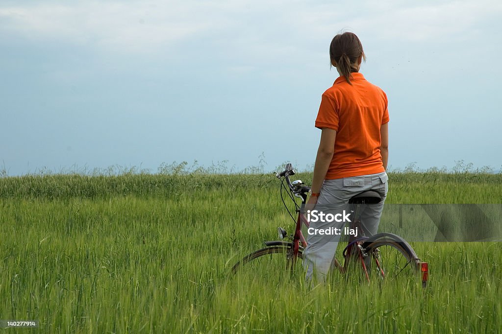 Menina sentada na bicicleta em campo verde - Royalty-free Admirar a Vista Foto de stock