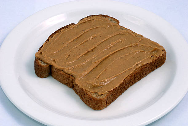 Natural peanut butter on whole wheat bread stock photo