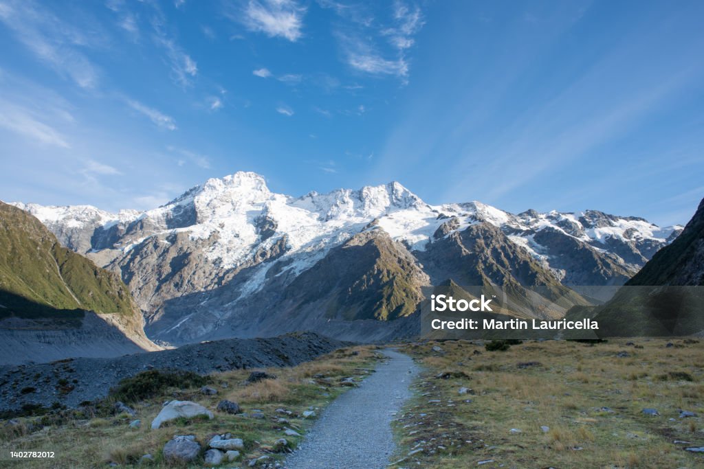 Hooker Valley track A hiking path leads towards snow capped mountains on a sunny day New Zealand Stock Photo