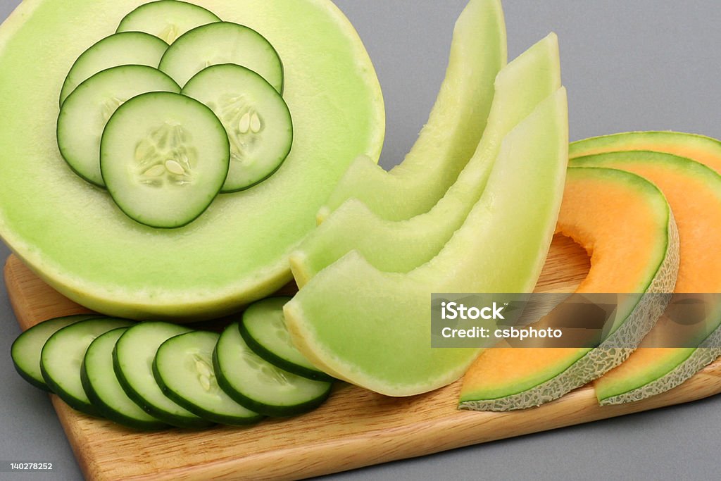 Cucumber melon 2 Photo of sliced cucumber, honeydew and cantaloupe on a cutting board with grey back ground Melon Stock Photo