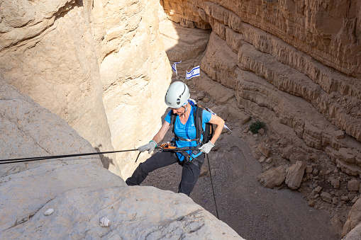 Jerusalem, Israel, May 05, 2022 : Experienced athlete on Israel Independence Day descending with equipment for rappel in mountains of Judean Desert, near Khatsatson stream, near Jerusalem, Israel.
