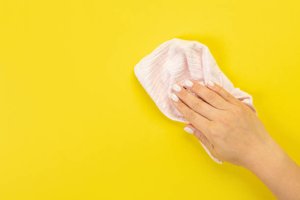 istock A housewife's hand holds a rag for dusting or washing. Empty space for text or logo on a yellow background. Early spring or regular cleaning. Cleaning and cleaning concept. 1402785500