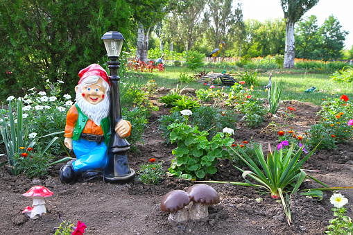 Decorative decorations of the garden. Lantern in the form of a gnome in the garden area. Elements of landscape design.