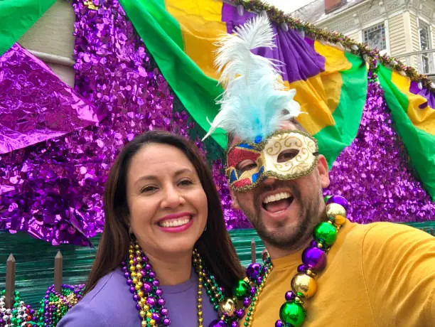 Happy latin tourists friends / heterosexual couple celebrating their Honeymoon in Mardi Gras in New Orleans dressing necklace and masks. Mardi Gras is the most important celebration for the city.