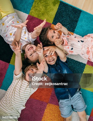 istock Smiling teacher and little child talking and playing at preschool 1402788196