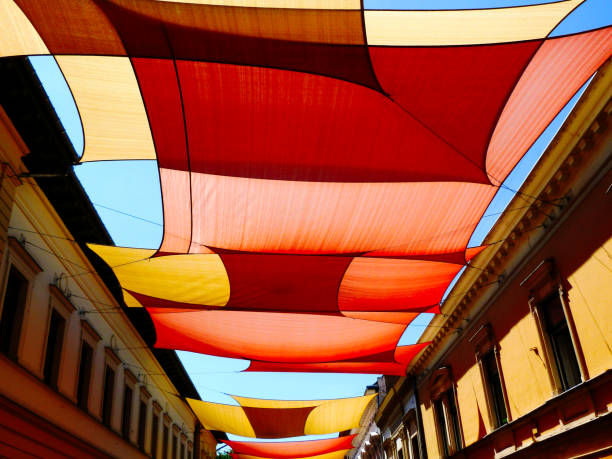 colorful canvas sun protection awnings over old european shopping street. stock photo