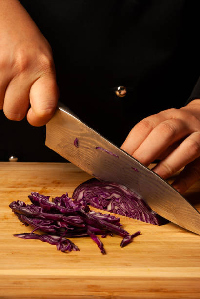 istock Chef's hands cutting a red cabbage, close-up - stock photo 1402793334