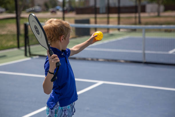 Boy playing pickle ball Young caucasian boy playing pickle ball on a hot summer day. pickleball stock pictures, royalty-free photos & images