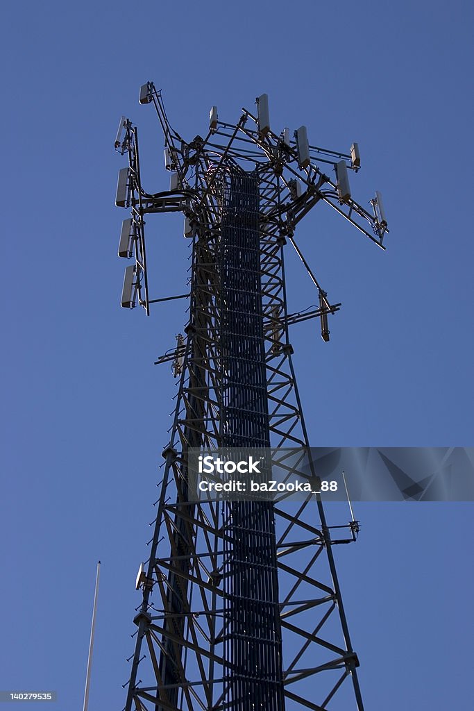 Cell tower against a blue sky. A cellular communications tower. Blue Stock Photo