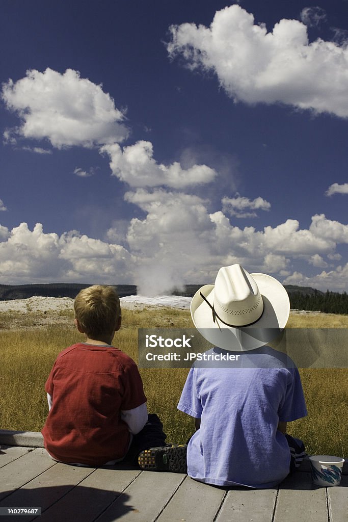 Waiting on Old Faithful Two boys waiting patiently for the Old Faithful geyser to erupt Yellowstone National Park Stock Photo