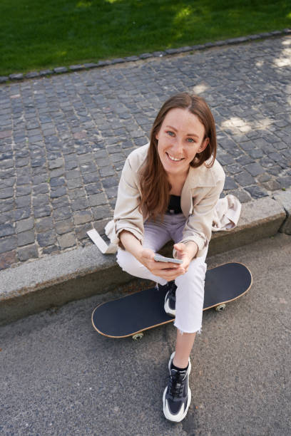 istock Lady sits on sidewalk putting her feet on the skateboard 1402797497