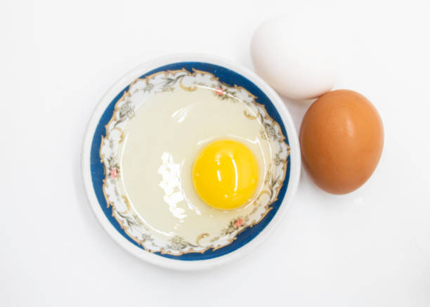 Two whole eggs and one broken isolated on a white background. stock photo