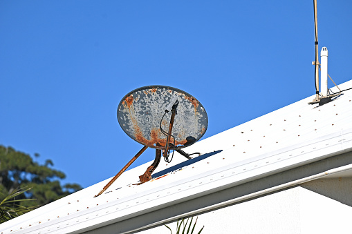 Rusty satellite dish on a house roof