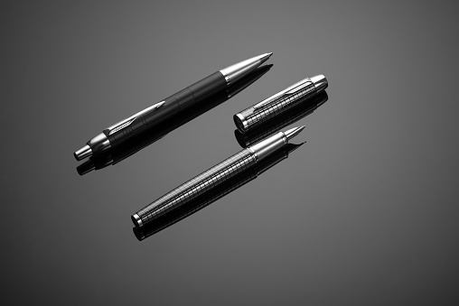 A closeup of fashionable ink pens on a black background