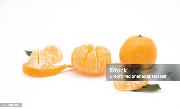 Tangerine Or Kamala Pieces With Green Leaf Isolated On White Background Stock Photo - Download Image Now