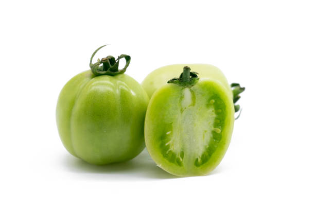 istock Whole and halved green unripe tomatoes isolated on white background. 1402802135